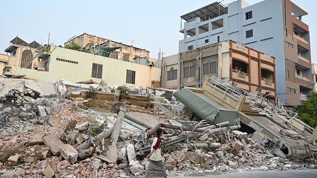 A woman walks past destroyed buildings in Mandalay, days after a 7.7 magnitude earthquake struck Myanmar.